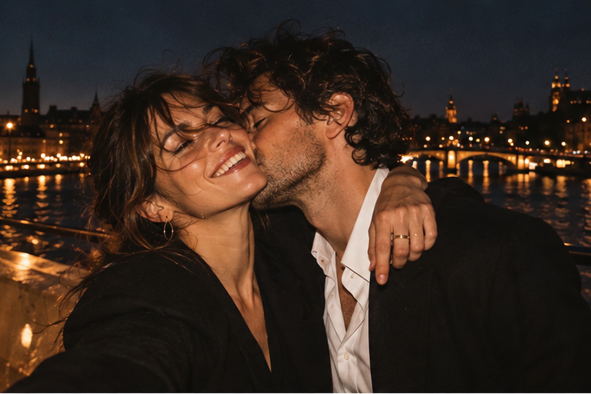 Sofia och Carl vid vattnet i Stockholm om kvällen. Han kysser henne på kinden och hon ler med slutna ögon, med stadens ljus bakom dem.